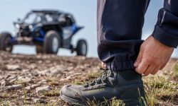A person wearing rugged leather overlanding boots resting their feet on a truck tailgate.
