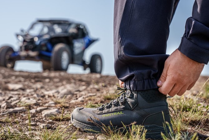 A person wearing rugged leather overlanding boots resting their feet on a truck tailgate.