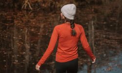 A camper wearing a Merino wool base layer sitting on the tailgate of a truck, drinking coffee on a cold morning.
