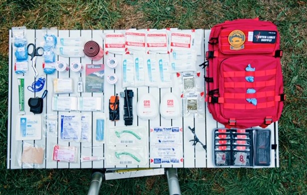 A comprehensive overlanding first aid and trauma kit opened on the tailgate of an off-road truck.