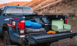 A stealth truck bed camping setup in an urban parking lot at night.