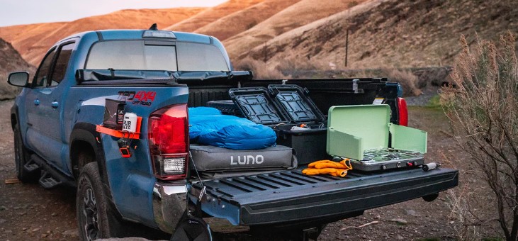 A stealth truck bed camping setup in an urban parking lot at night.